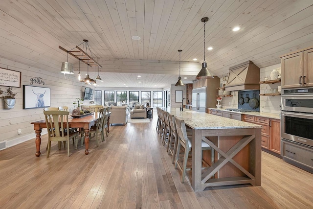 kitchen with light stone countertops, pendant lighting, wooden ceiling, and appliances with stainless steel finishes