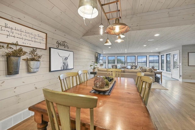 dining area featuring hardwood / wood-style flooring, wooden ceiling, and wooden walls