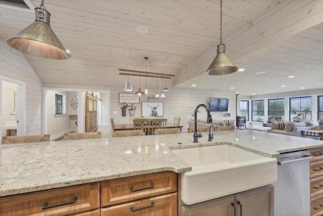 kitchen featuring light stone countertops, wooden walls, sink, pendant lighting, and wooden ceiling