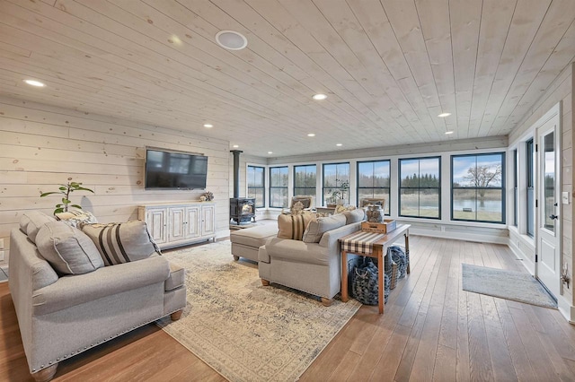 living room with a wood stove, plenty of natural light, wooden ceiling, and light wood-type flooring