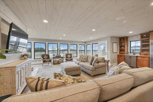 living room featuring sink, light wood-type flooring, wood walls, and wood ceiling