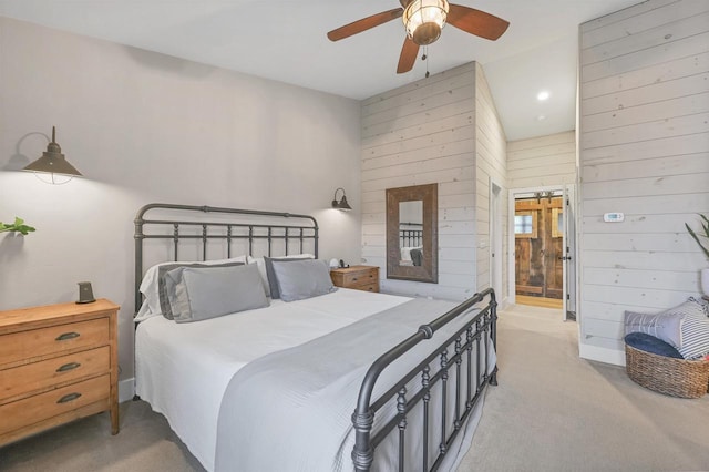 carpeted bedroom featuring wood walls, ceiling fan, and ensuite bathroom