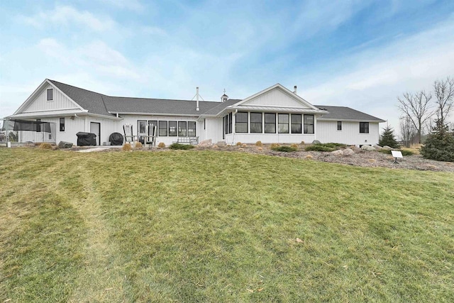 rear view of house featuring a sunroom and a yard