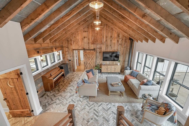 living room with beam ceiling, a barn door, high vaulted ceiling, parquet flooring, and wooden walls