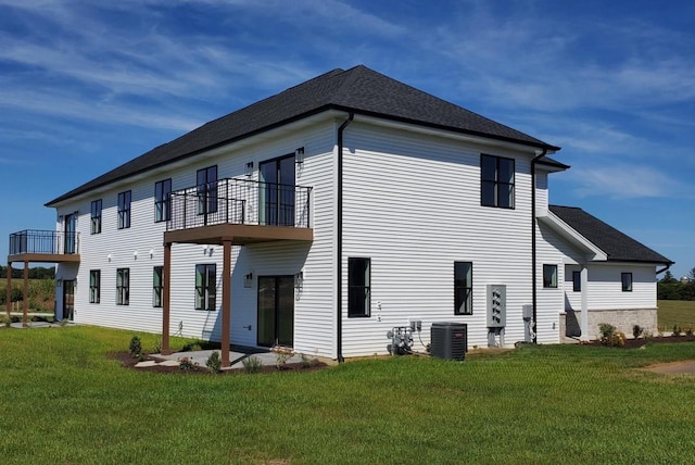 rear view of house with a lawn, central air condition unit, and a balcony