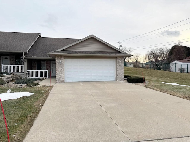 view of front of house featuring covered porch, a garage, and a front lawn