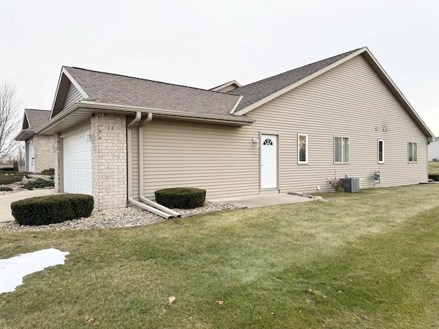 rear view of property featuring central AC, a garage, and a lawn