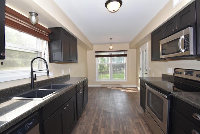 kitchen featuring dark hardwood / wood-style flooring, stainless steel appliances, hanging light fixtures, and sink