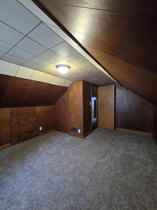 bonus room with wooden walls, carpet floors, and vaulted ceiling