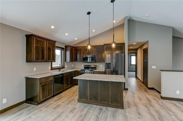 kitchen featuring sink, hanging light fixtures, stainless steel appliances, light stone counters, and a kitchen island