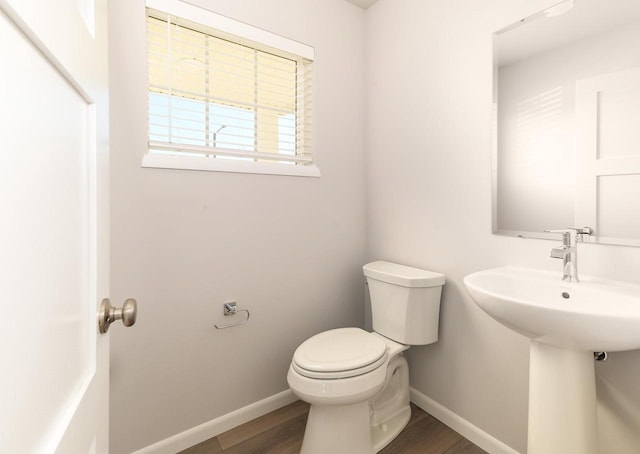 bathroom with toilet, baseboards, and wood finished floors