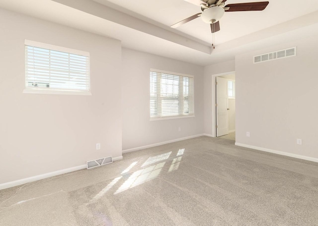 unfurnished room with visible vents, a raised ceiling, and baseboards