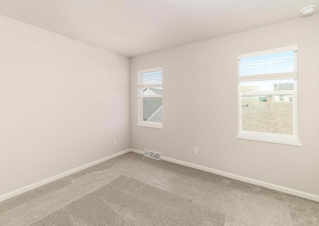 spare room featuring baseboards, light carpet, and visible vents