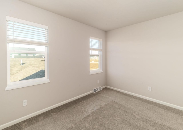 unfurnished room with carpet, visible vents, and baseboards