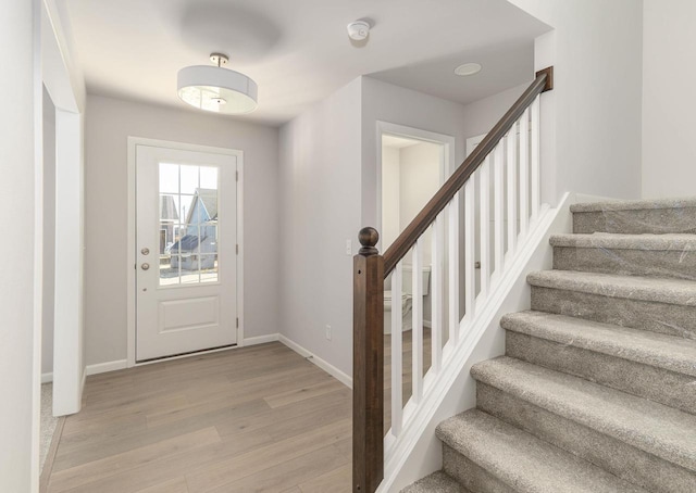 foyer with stairway, baseboards, and light wood-style flooring