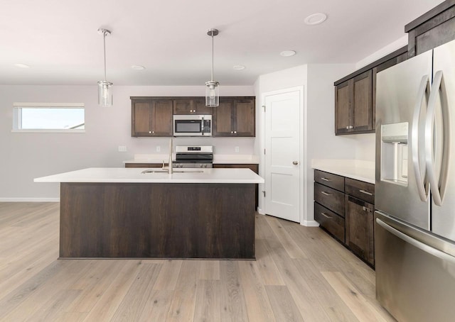 kitchen with a sink, stainless steel appliances, light countertops, dark brown cabinets, and light wood-type flooring