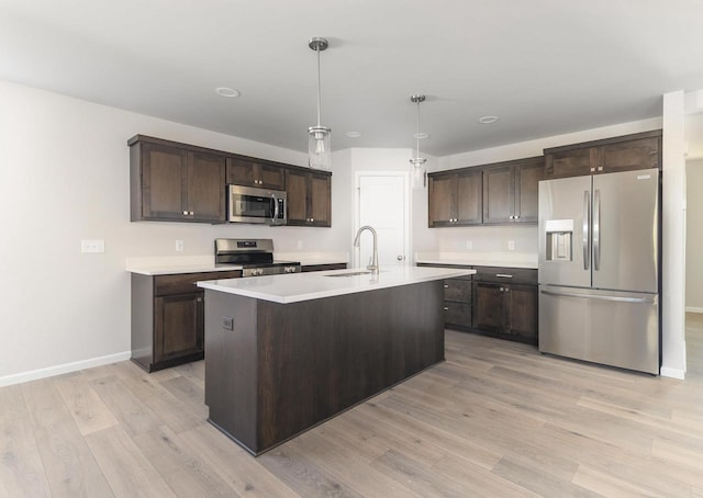 kitchen with light wood finished floors, a sink, light countertops, dark brown cabinets, and appliances with stainless steel finishes