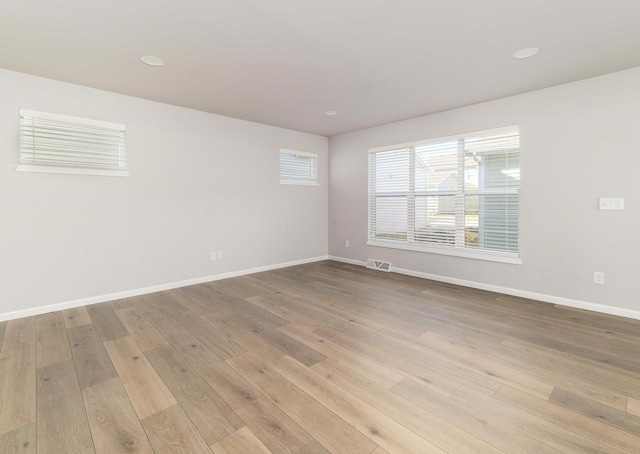 spare room featuring visible vents, baseboards, and light wood-style floors