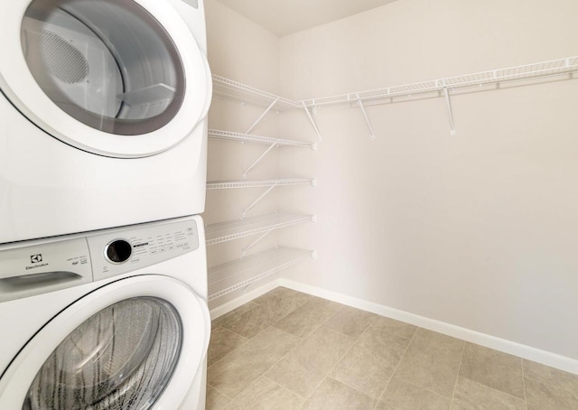 laundry room with laundry area, baseboards, and stacked washer and dryer