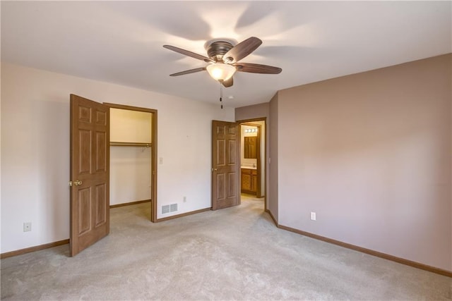 unfurnished bedroom featuring connected bathroom, ceiling fan, a spacious closet, light carpet, and a closet