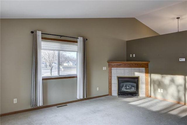 unfurnished living room with carpet floors, lofted ceiling, and a tiled fireplace