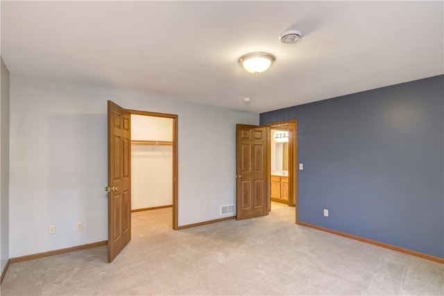 unfurnished bedroom with a spacious closet, a closet, and light carpet