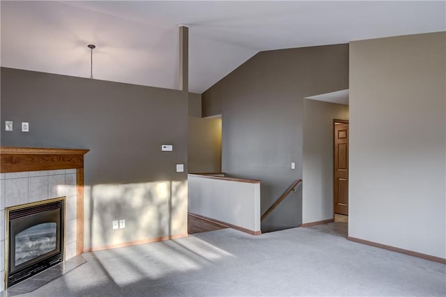 unfurnished living room with a tile fireplace, carpet floors, and lofted ceiling