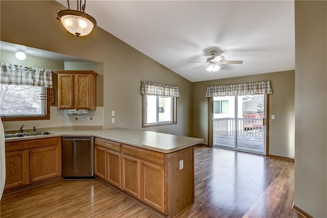 kitchen with kitchen peninsula, dishwasher, light hardwood / wood-style flooring, and sink