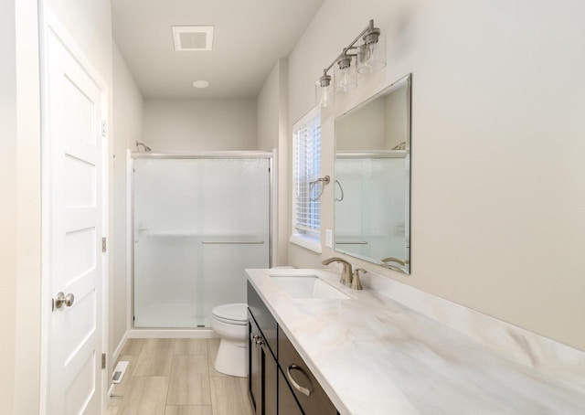 full bathroom featuring visible vents, a shower stall, toilet, and vanity