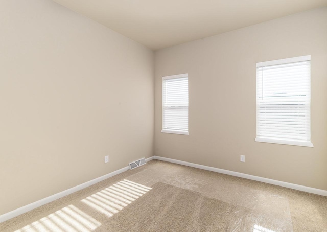 unfurnished room featuring visible vents, baseboards, and light carpet