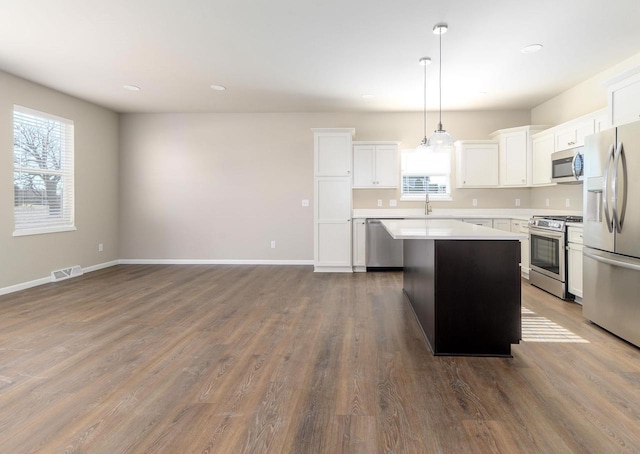 kitchen featuring a healthy amount of sunlight, appliances with stainless steel finishes, a center island, and light countertops