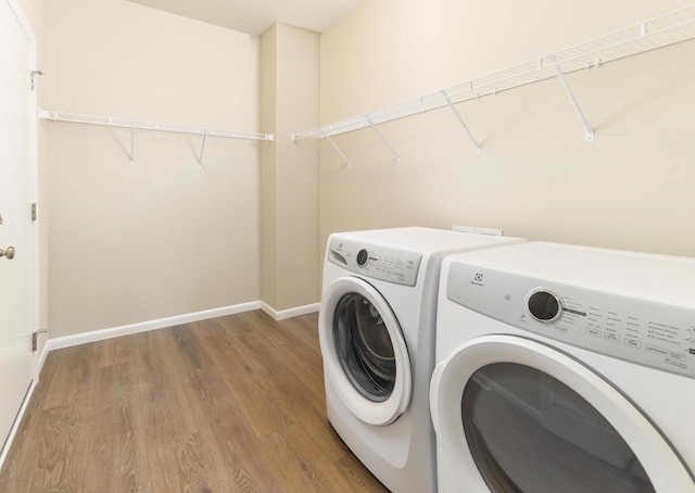 laundry area featuring laundry area, washer and dryer, baseboards, and wood finished floors