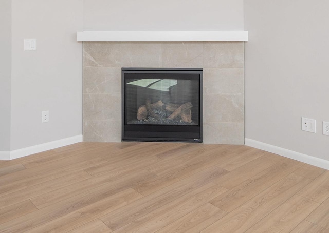 interior details with hardwood / wood-style flooring and a tiled fireplace