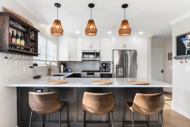 kitchen featuring sink, pendant lighting, light hardwood / wood-style flooring, high quality appliances, and white cabinetry