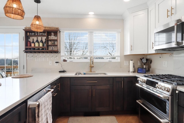 kitchen with sink, white cabinetry, stainless steel appliances, and hanging light fixtures