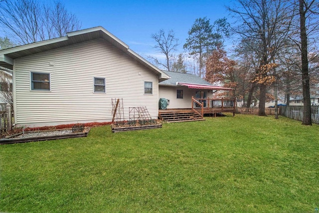 rear view of house featuring a wooden deck and a yard