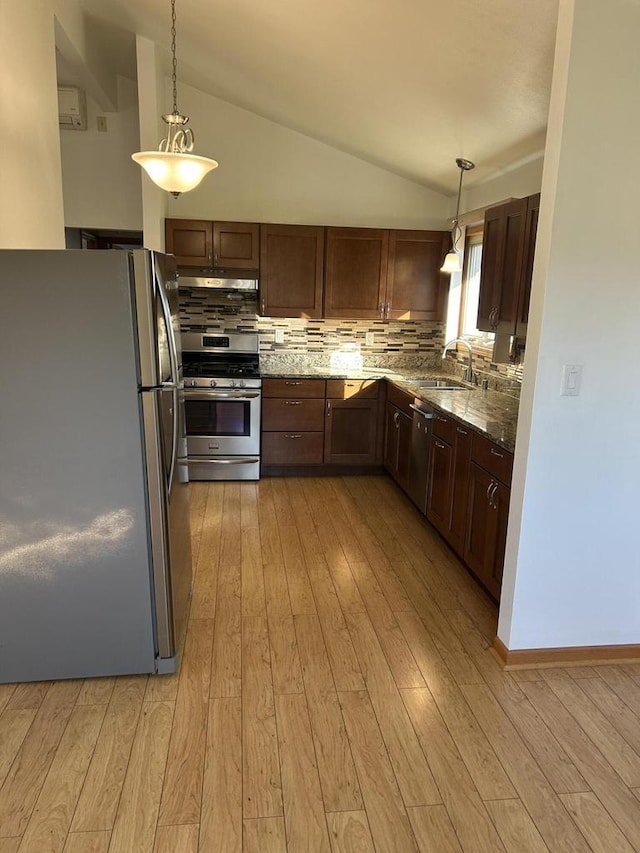 kitchen featuring sink, tasteful backsplash, decorative light fixtures, vaulted ceiling, and appliances with stainless steel finishes