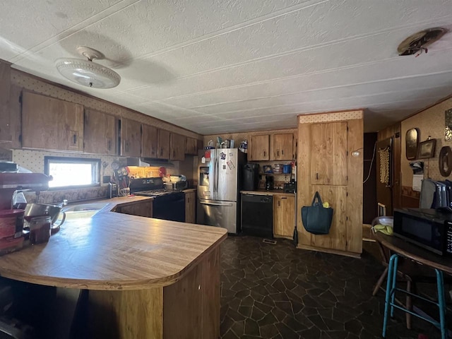 kitchen with black appliances, kitchen peninsula, sink, and a textured ceiling