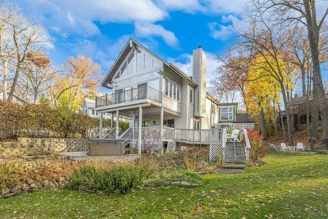 rear view of property featuring a lawn, a balcony, a deck, and a hot tub