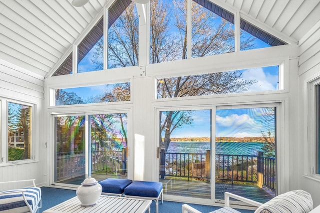 sunroom with plenty of natural light, a water view, and vaulted ceiling