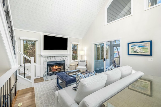 living room featuring a wealth of natural light, a high end fireplace, wood-type flooring, and high vaulted ceiling