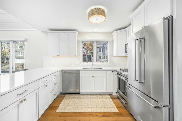 kitchen with premium appliances, white cabinetry, and sink