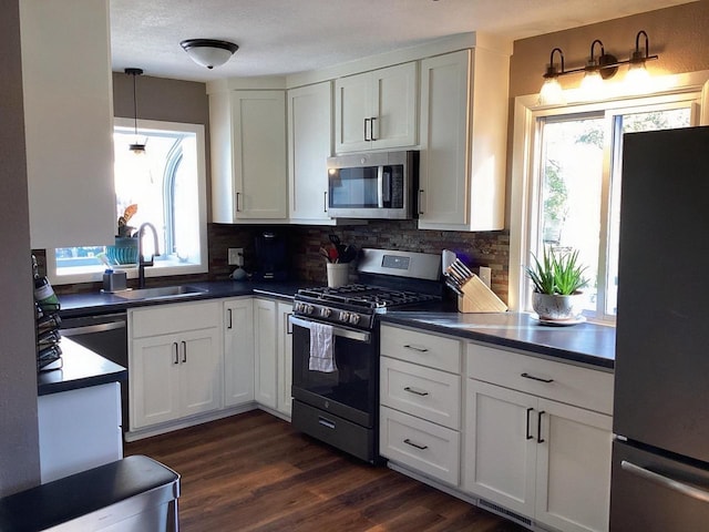 kitchen with sink, a healthy amount of sunlight, stainless steel appliances, tasteful backsplash, and white cabinets