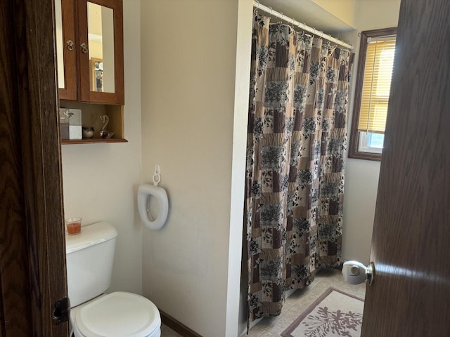 bathroom featuring tile patterned floors, toilet, and curtained shower