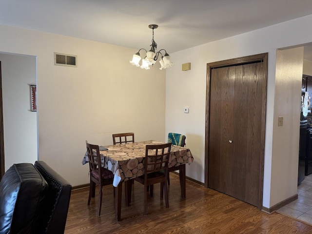 dining space with hardwood / wood-style flooring and a notable chandelier