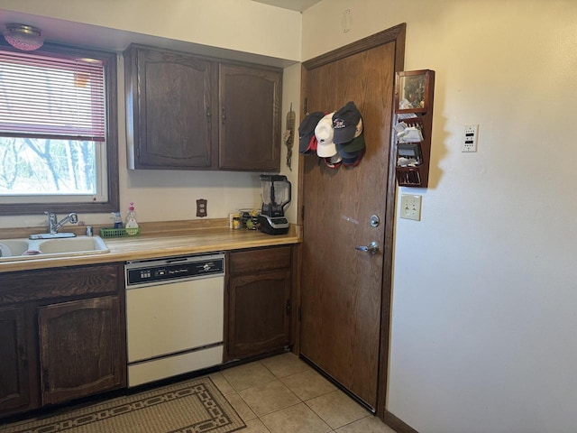 kitchen featuring white dishwasher, dark brown cabinetry, sink, and light tile patterned floors