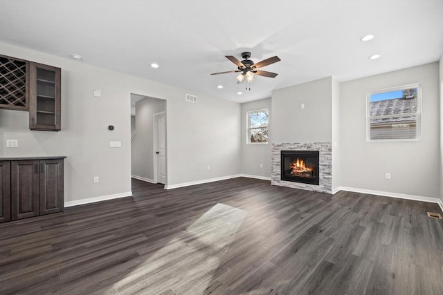 unfurnished living room with a fireplace, ceiling fan, and dark wood-type flooring