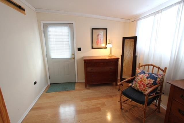 living area with light hardwood / wood-style floors and crown molding