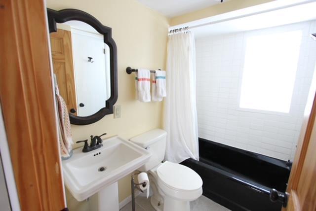 full bathroom with toilet, shower / bathtub combination with curtain, and sink