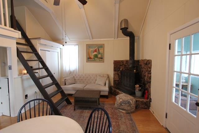 living room with vaulted ceiling, hardwood / wood-style flooring, a wood stove, and ceiling fan